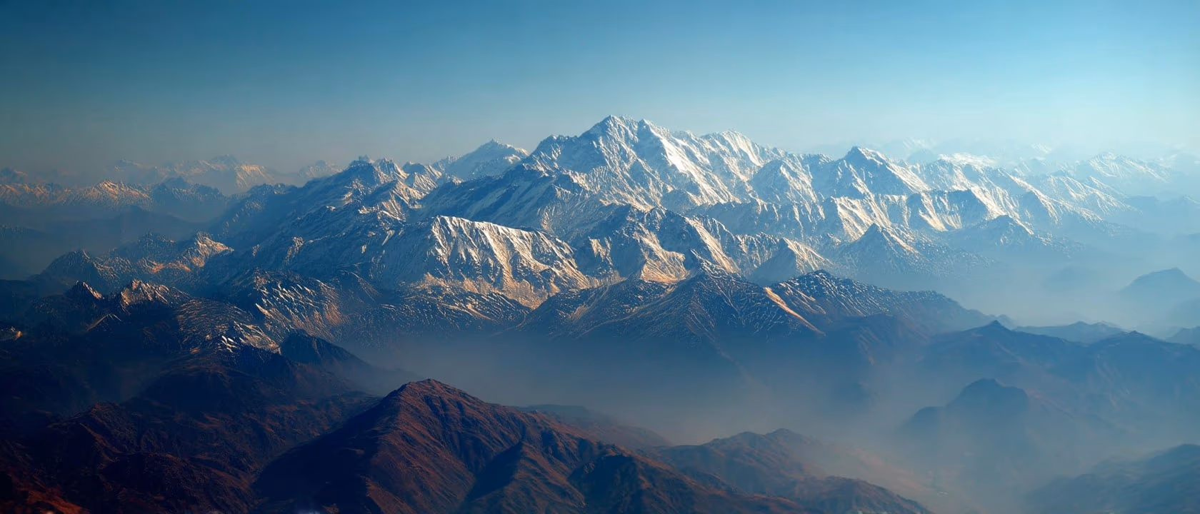 An aerial view of the Hindu Kush range, its snow-capped peaks fading into successive layers of haze.
